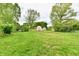 Large grassy backyard with storage shed, partially surrounded by fencing and mature trees at 135 Hickory Ct, Greenwood, IN 46142