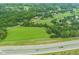 Expansive aerial view of a lush property with a large green field and surrounding mature trees near a highway at 14655 Little Eagle Creek Ave, Zionsville, IN 46077