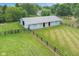 Aerial view of a barn surrounded by a black fence, complemented by lush greenery and a peaceful country landscape at 14655 Little Eagle Creek Ave, Zionsville, IN 46077