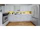 Bright kitchen features white cabinetry, stone backsplash, stainless steel appliances, and hardwood flooring at 14655 Little Eagle Creek Ave, Zionsville, IN 46077