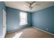 Empty blue bedroom with ceiling fan, neutral carpeting, and a single window for natural light at 16156 Oliver St, Fishers, IN 46037