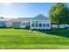 Rear exterior view showcasing a sunroom addition with a lush green lawn at 16156 Oliver St, Fishers, IN 46037