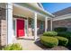 Inviting front porch with brick columns and lush landscaping leading to a bold red entrance door at 16156 Oliver St, Fishers, IN 46037