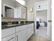 Bathroom with a double vanity, white cabinets, a dark countertop, and a view into a bedroom at 16305 Kenora N Ln, Fortville, IN 46040