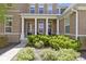 Inviting front porch with decorative pillars, black front door, and landscaped garden at 16305 Kenora N Ln, Fortville, IN 46040