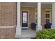 Close-up of a front porch featuring white columns, a black front door with glass, and outdoor seating at 16305 Kenora N Ln, Fortville, IN 46040