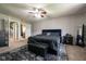 Well-lit bedroom with a black upholstered bed, ceiling fan, and doorway leading to the bathroom at 171 Williams Trce, Plainfield, IN 46168