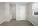 A clean, carpeted bedroom features two doors and a window letting in natural light at 1903 Danbury Dr, Indianapolis, IN 46231
