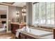 Elegant bathroom featuring soaking tub with custom tile surround, vanity with natural stone countertop, and soft gray walls at 2377 Finchley Rd, Carmel, IN 46032