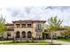 Elegant two-story home with a tiled roof, arched entryways, a balcony, and manicured landscaping at 2377 Finchley Rd, Carmel, IN 46032