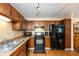 A well-lit kitchen featuring laminate floors, wooden cabinets, black appliances, and a tiled backsplash at 3131 Stillmeadow Dr, Indianapolis, IN 46214