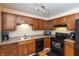 A well-lit kitchen featuring laminate floors, wooden cabinets, black appliances, and a tiled backsplash at 3131 Stillmeadow Dr, Indianapolis, IN 46214