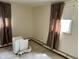 Bedroom with neutral carpeting and a window, featuring curtains and baseboard heaters at 318 Elva St, Anderson, IN 46013