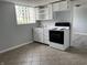 Compact kitchen featuring white cabinets and a range and a glass block window at 3720 E Southern Ave, Indianapolis, IN 46203