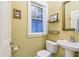 Bright bathroom with pedestal sink, patterned privacy window, and decorative wall hangings at 4169 Central Ave, Indianapolis, IN 46205