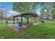 Outdoor picnic area with covered seating, BBQ grill, and trash bins near an open green space and recreational area at 4169 Central Ave, Indianapolis, IN 46205