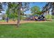 Community playground with slides, swings, and climbing structures set amongst lush green grass and mature trees at 4169 Central Ave, Indianapolis, IN 46205