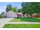 Inviting home with mature trees, red shutters, a charming porch, and a two-car garage at 4611 29Th St, Columbus, IN 47203