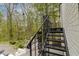 Exterior black metal staircase with a landing surrounded by lush greenery and a view of the backyard at 5190 Potters Pike, Indianapolis, IN 46234