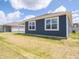 View of the home's exterior with blue siding and white trim, highlighting the lawn under a bright, cloudy sky at 5204 Cartland Dr, Indianapolis, IN 46239
