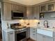 Well-equipped kitchen with stainless steel appliances, a farmhouse sink, and bright countertops at 5282 W Blue Bell Dr, New Palestine, IN 46163