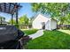Backyard featuring a well-manicured lawn, white garage, pergola, grill and concrete walkway at 544 N Beville Ave, Indianapolis, IN 46201