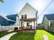 A lush backyard features a wooden deck with a pergola, outdoor seating, grill, manicured lawn, and modern white siding at 544 N Beville Ave, Indianapolis, IN 46201
