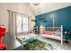 Bright bedroom featuring a white crib, hardwood floors, a blue accent wall, and a colorful rug at 544 N Beville Ave, Indianapolis, IN 46201