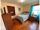 Comfortable bedroom featuring hardwood floors, a cozy bed, and a shelved wicker cabinet at 5450 E 18Th St, Indianapolis, IN 46218