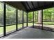 A view from inside the screened porch, looking out onto a lush green yard surrounded by mature trees at 5548 Painted Maple Ct, Indianapolis, IN 46254