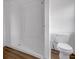 A bathroom with a toilet and a shower with shelves along the back wall and wood floors and bright white walls at 555 S Auburn St, Indianapolis, IN 46241