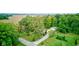 Aerial view of a tree-lined property with a long driveway, a detached garage, and surrounding farmland at 5750 W 650 N, Thorntown, IN 46071