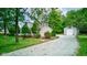 Cozy home with a gravel driveway and a detached garage, surrounded by mature trees and a green lawn at 5750 W 650 N, Thorntown, IN 46071