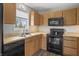 Well-equipped kitchen featuring black appliances, wood cabinets, and laminate flooring at 6231 W Clinton St, Stilesville, IN 46180
