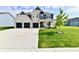 Spacious white brick home featuring a three-car garage, lush green lawn, and modern architectural details at 6398 Marden Trl, Brownsburg, IN 46112