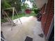 View of the brick house and backyard area, including a concrete patio with swing and chairs, and a small red shed at 7017 Mc Lain Dr, Indianapolis, IN 46217
