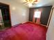 This cozy bedroom features red carpet, a ceiling fan, and natural light streaming in through the window at 7017 Mc Lain Dr, Indianapolis, IN 46217