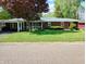 Inviting brick home featuring a well-maintained lawn, mature landscaping, and a convenient carport at 7017 Mc Lain Dr, Indianapolis, IN 46217