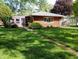 Well-kept brick home with mature landscaping, a small walkway, and a cozy, welcoming facade at 7017 Mc Lain Dr, Indianapolis, IN 46217