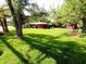 Picturesque view of the property with a spacious lawn, mature trees, and a charming shed, enhancing the home's curb appeal at 7017 Mc Lain Dr, Indianapolis, IN 46217