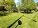 Sprawling lawn dotted with mature trees, highlights this brick ranch with covered carport on a sunny day at 7017 Mc Lain Dr, Indianapolis, IN 46217