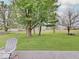 A large, grassy backyard is enhanced by mature trees and a picnic table at 710 Marie Ln, Fortville, IN 46040