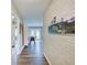 Hallway featuring wood-look flooring, brick wall and mountain painting leading to living spaces at 710 Marie Ln, Fortville, IN 46040