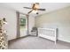 Bright Bedroom showcasing a crib, chair, neutral tones, ceiling fan and natural light through large windows at 7135 Lantern Rd, Indianapolis, IN 46256