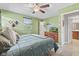 Light green bedroom with ceiling fan, a wooden dresser, a window view, and a comfortable setting at 7153 N Audubon Rd, Indianapolis, IN 46250