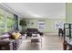 Spacious living room with green walls, wood floors, a large window, and comfortable leather seating at 7153 N Audubon Rd, Indianapolis, IN 46250