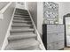 Carpeted staircase leading upstairs, complemented by modern art and a decorative cabinet on the side at 7153 N Audubon Rd, Indianapolis, IN 46250