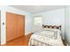 A bedroom featuring hardwood floors, a cozy bed, and a window with bright sunlight at 7250 Hoover Rd, Indianapolis, IN 46260