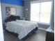Bedroom with a large window and plank flooring with gray and blue accent wall at 7897 Hickory Ridge Ln, Mooresville, IN 46158