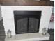 Close up of stone fireplace with wooden mantel and black mesh screen and decorative lanterns at 7897 Hickory Ridge Ln, Mooresville, IN 46158